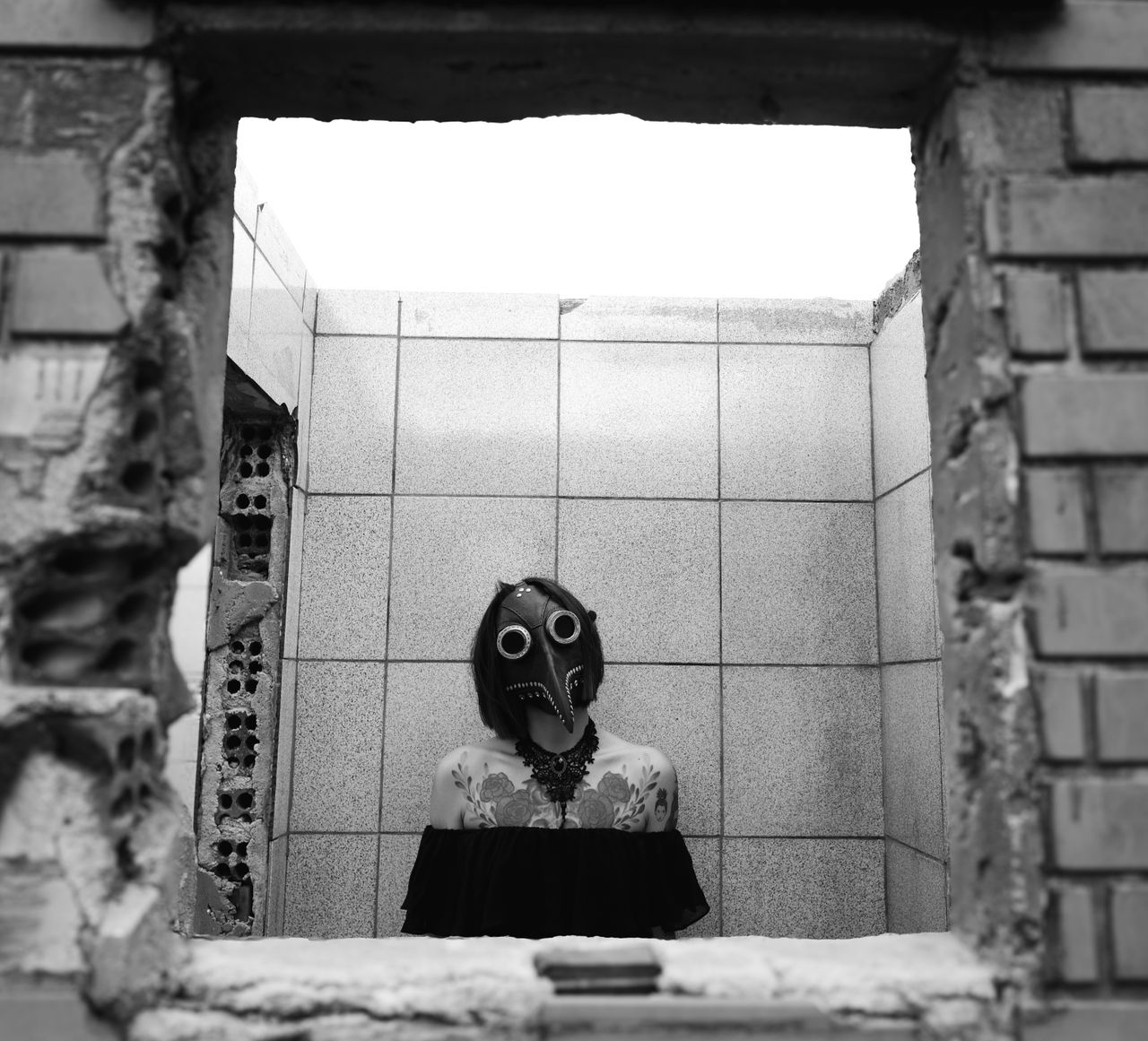 black and white photo of a masked figure standing inside a dilapidated