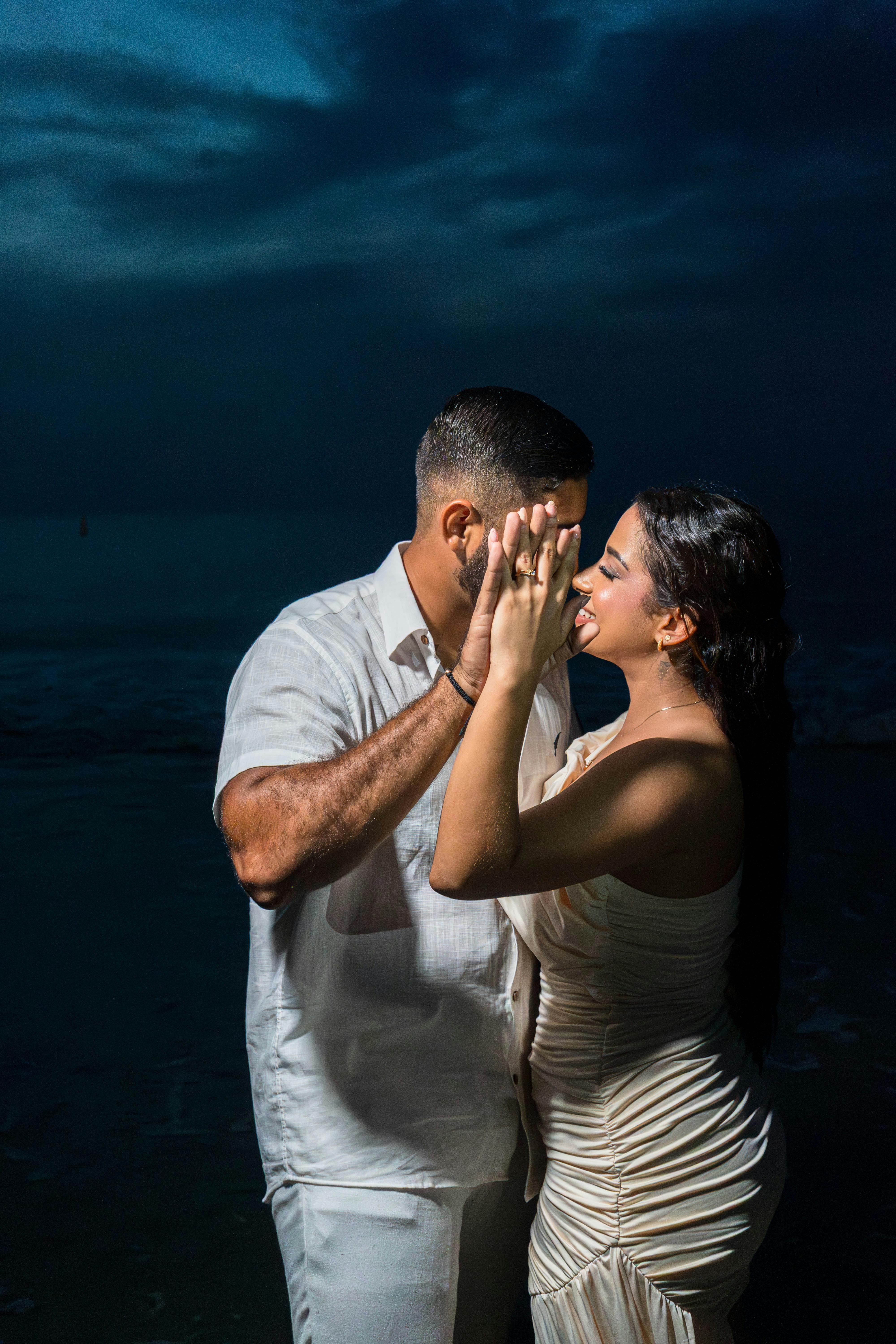 A couple shares a romantic dance by the ocean at twilight, embracing each other warmly.