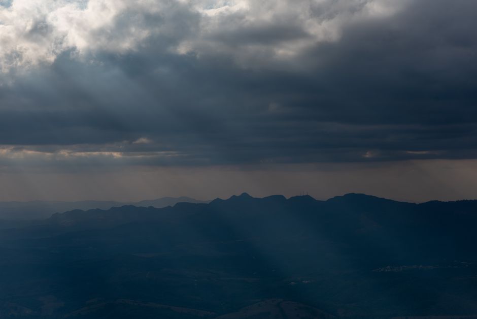 Sunbeams piercing through clouds over mountains in Minas Gerais, Brazil.