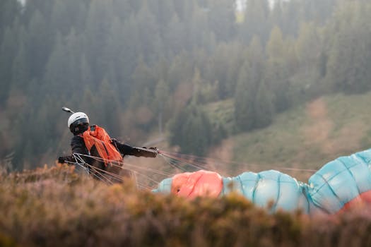 A paraglider prepares for launch in a forested mountain area, capturing adventure and outdoor excitement.