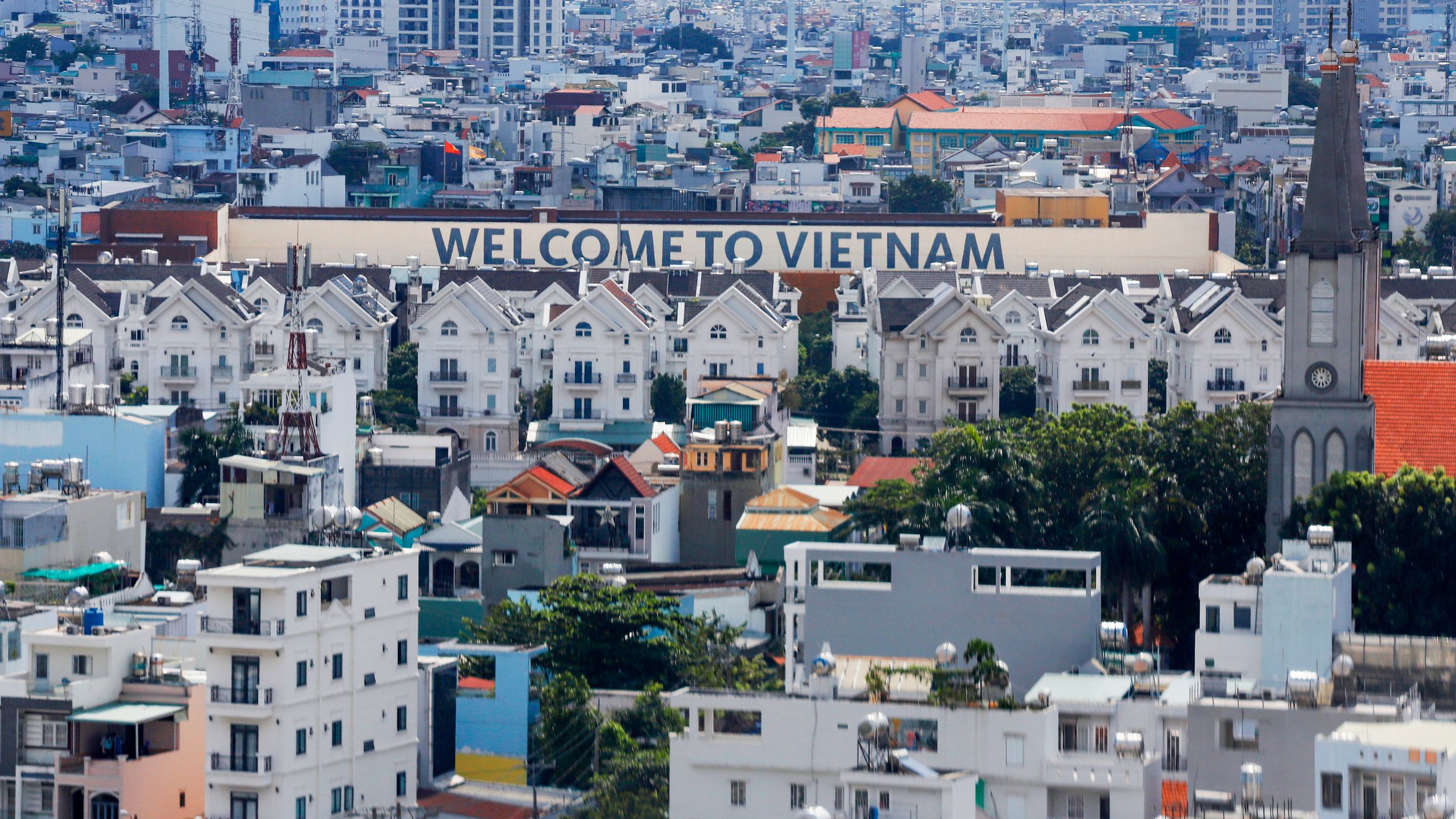 A vibrant aerial view of Ho Chi Minh City featuring the iconic 'Welcome to Vietnam' sign among buildings.