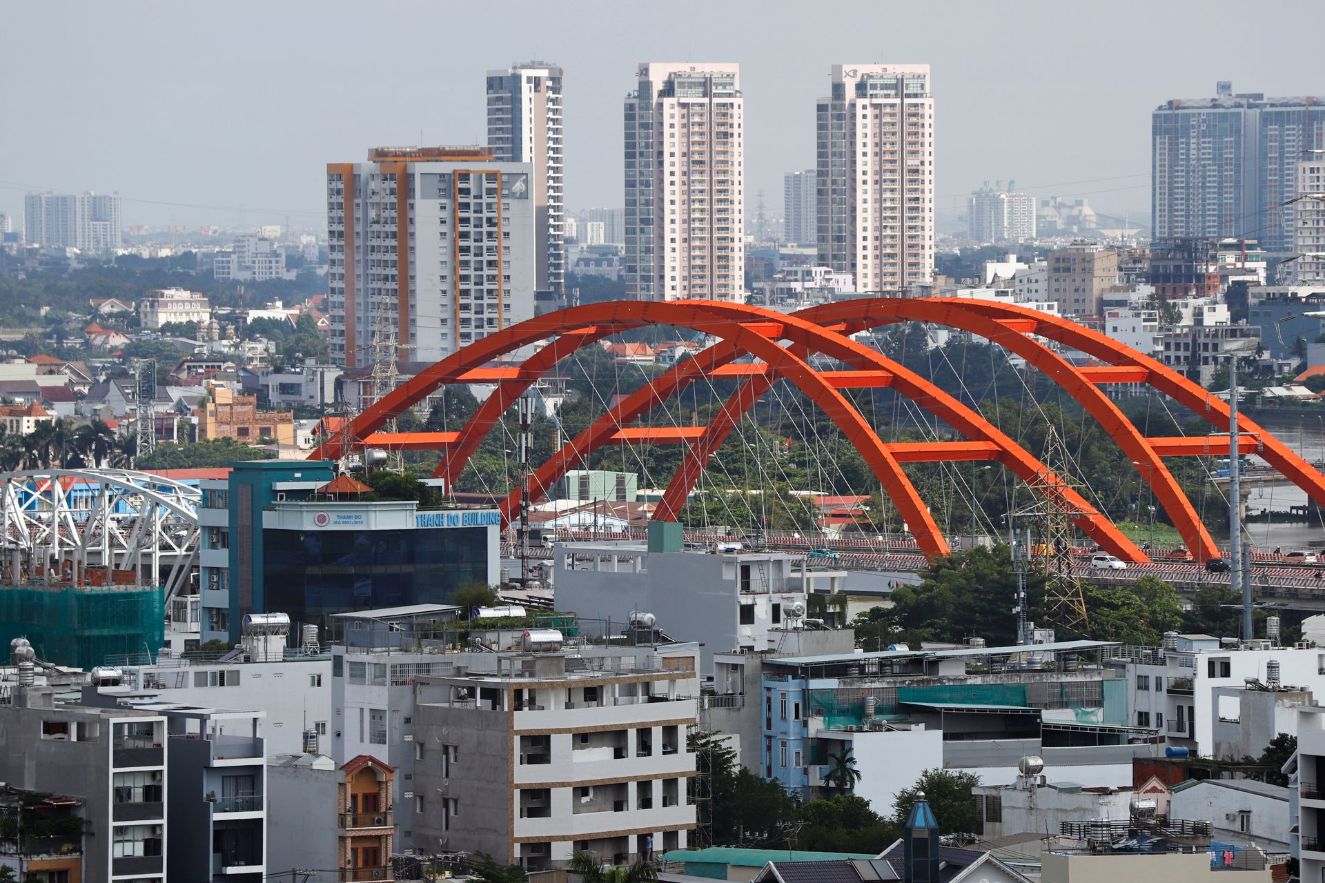 A vibrant urban landscape featuring a striking red bridge amid towering high-rises.