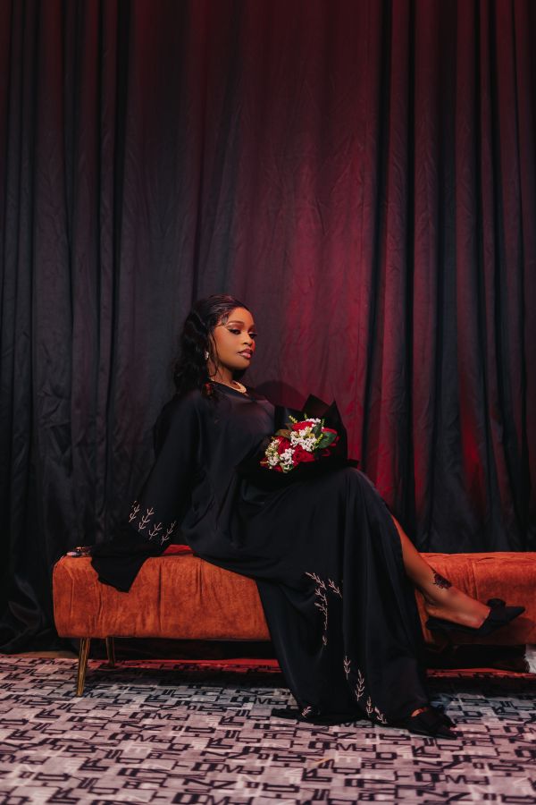Woman in a black dress holding a bouquet on an orange couch