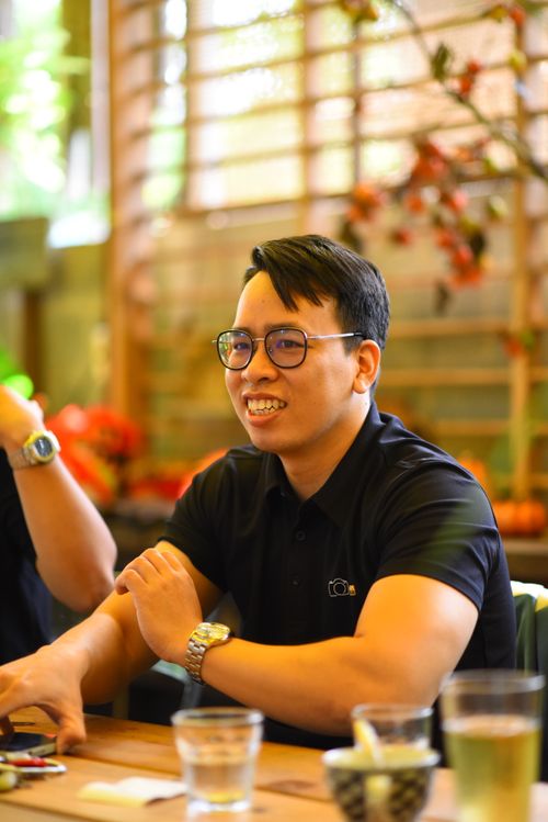 Free Man smiling while enjoying a casual indoor lunch with friends, lively atmosphere. Stock Photo