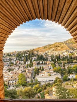 Beautiful view of Granada city framed by an Alhambra arch with hills and skyline.