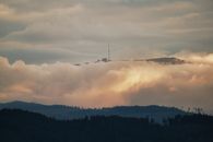 A breathtaking view of clouds enveloping the Tatra Mountains with a radio tower at sunset.