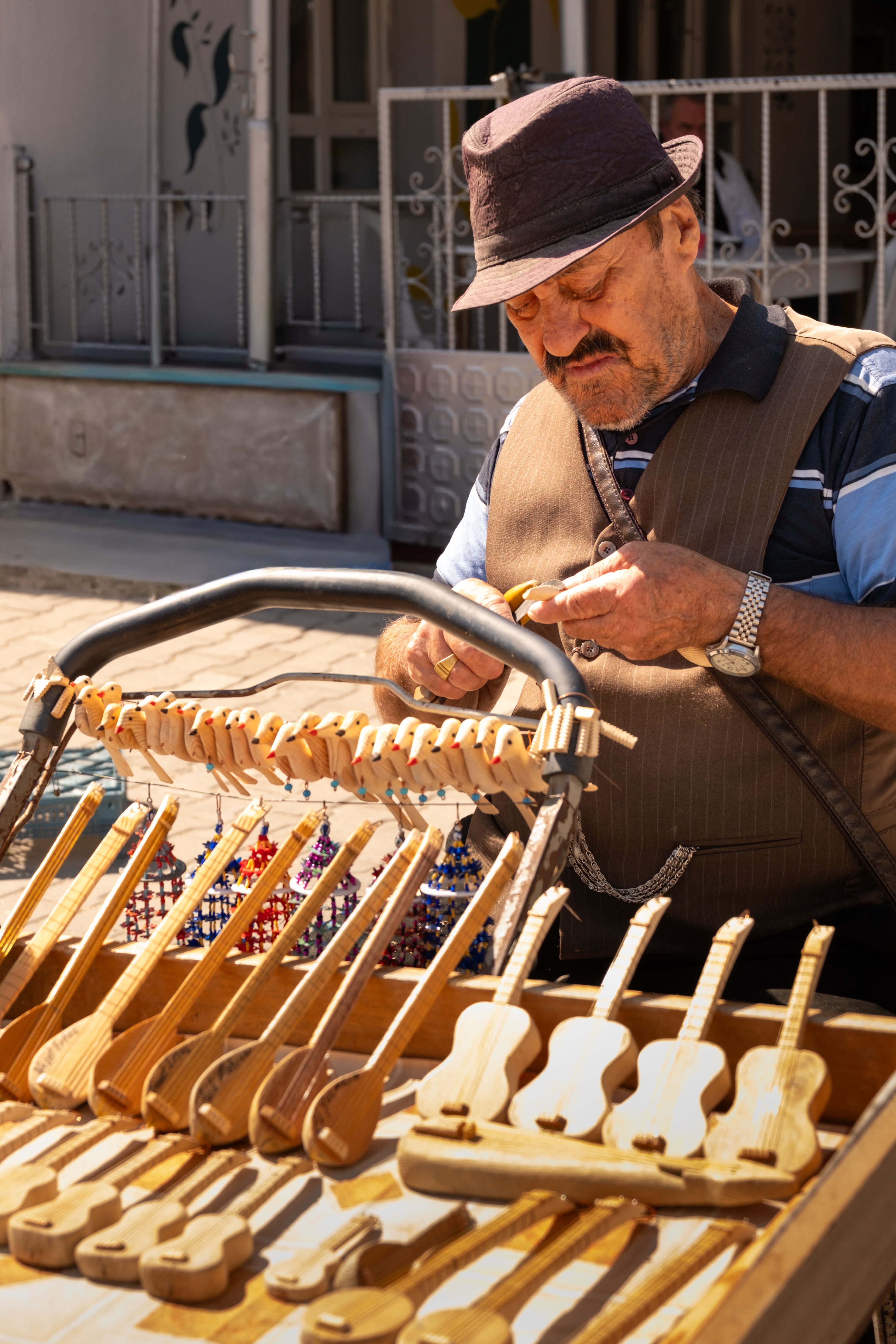 Artisan crafting wooden instruments at a street market, emphasizing craftsmanship and culture.