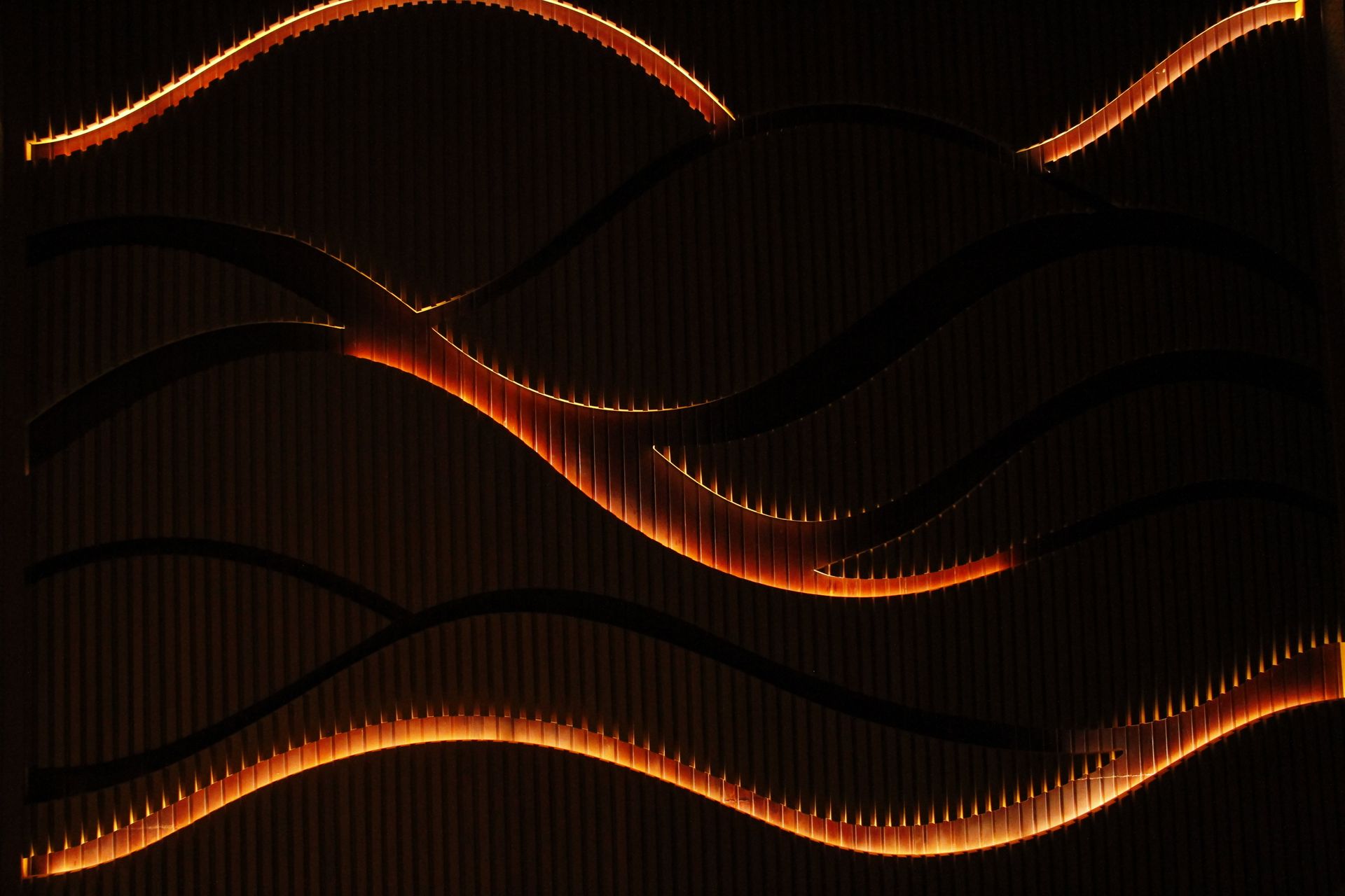 Curved light patterns create an artistic wave effect on a textured dark background.