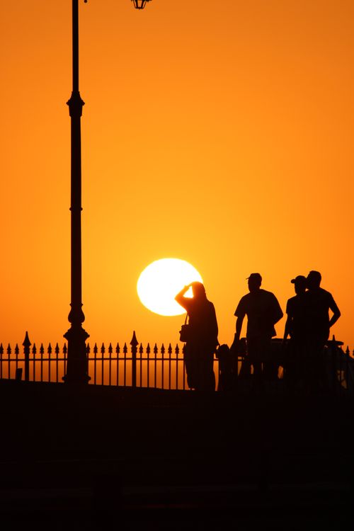 Free Silhouetted figures against a vibrant orange sunset in Morocco. Stock Photo