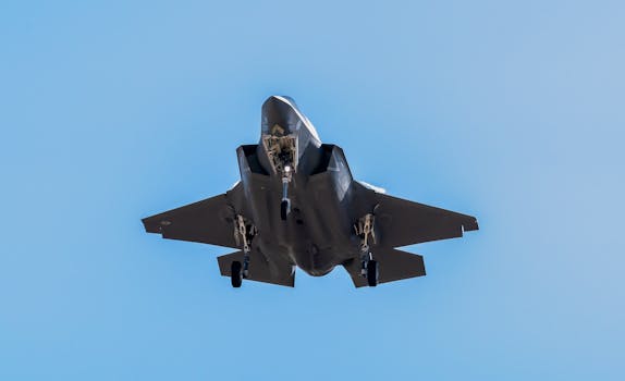 F-35 fighter jet flying over Los Llanos Air Base, clear sky view.
