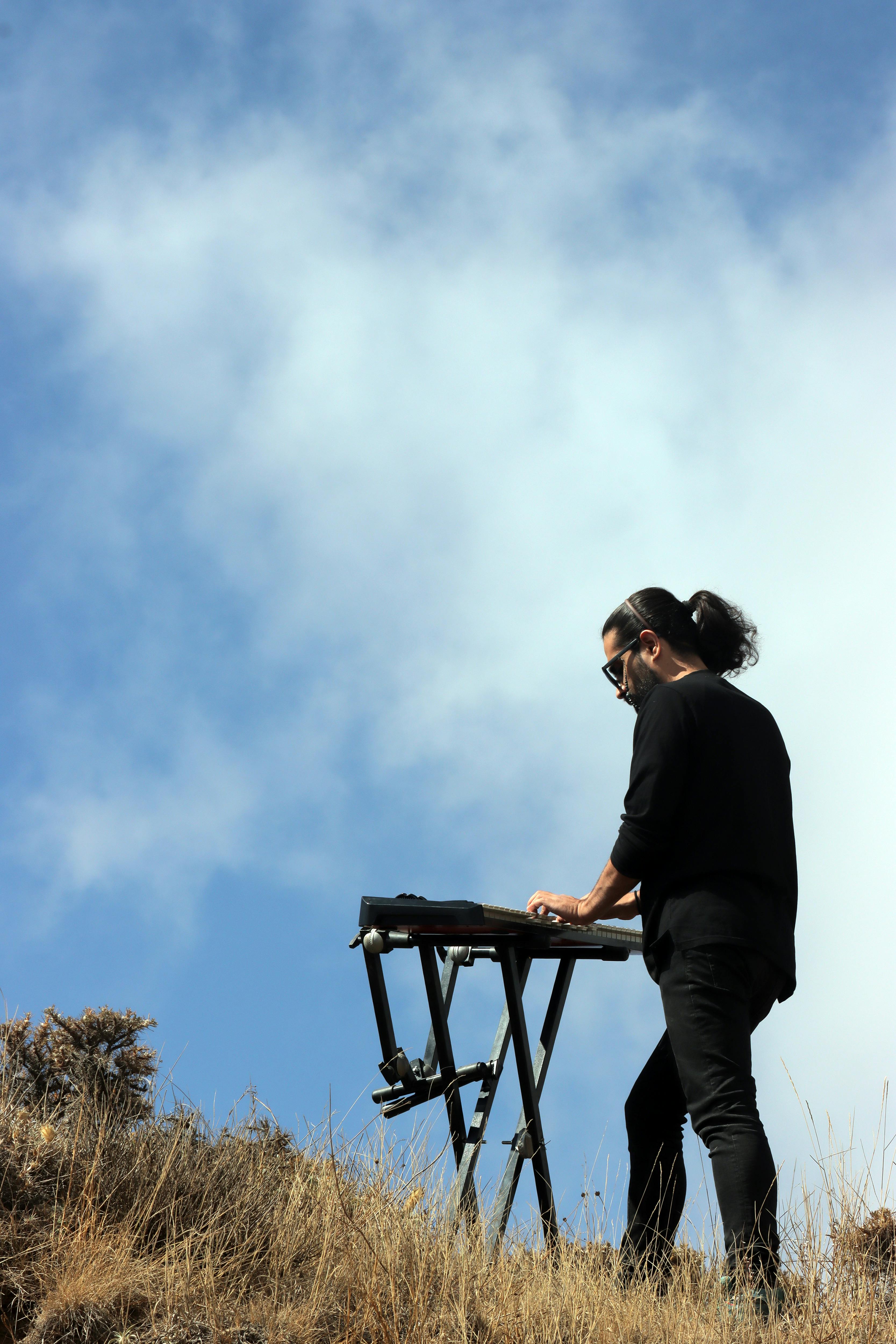 Musician with keyboard performing outdoors against clear blue sky in Qazvin Province.