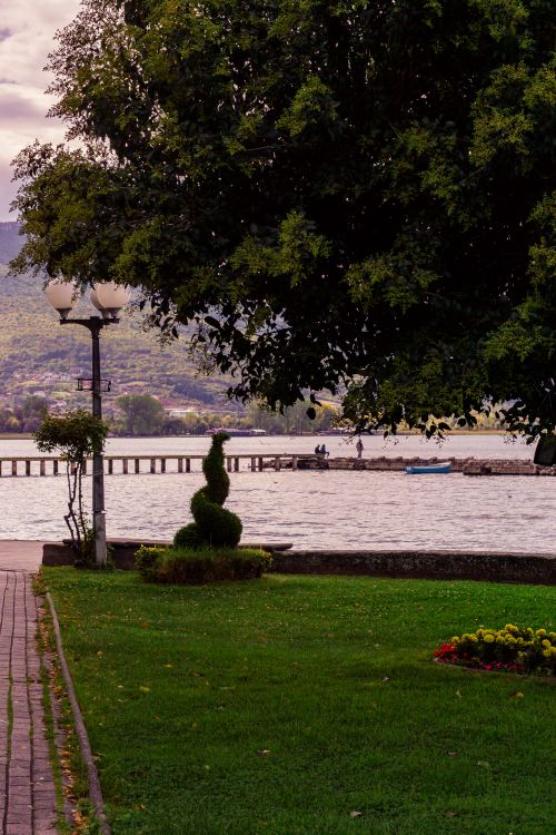 Free Tranquil lakeside scene with greenery, trees, and distant mountains in Ohrid. Stock Photo