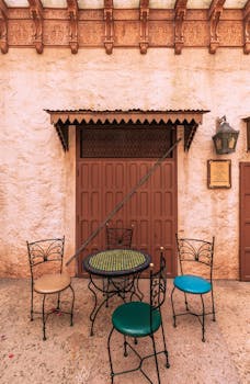 Inviting Moroccan-style patio with ornate metal chairs and a textured wall in a theme park setting.