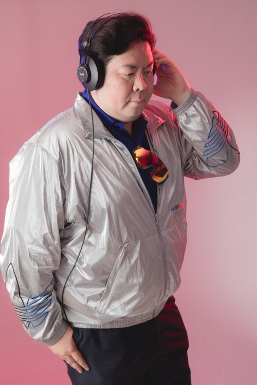 Free Man wearing headphones and a silver retro style jacket, stylish and focused. Stock Photo