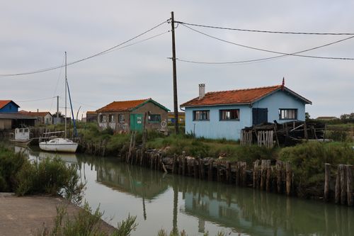 Free A picturesque canal scene with rustic houses and docked boats under a cloudy sky. Stock Photo