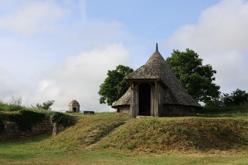 Free A medieval wooden hut sits in a serene grassy landscape under a blue sky. Stock Photo