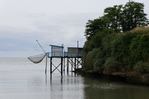 Free A peaceful coastal scene featuring a fishing hut on stilts with a net extended over calm waters. Stock Photo