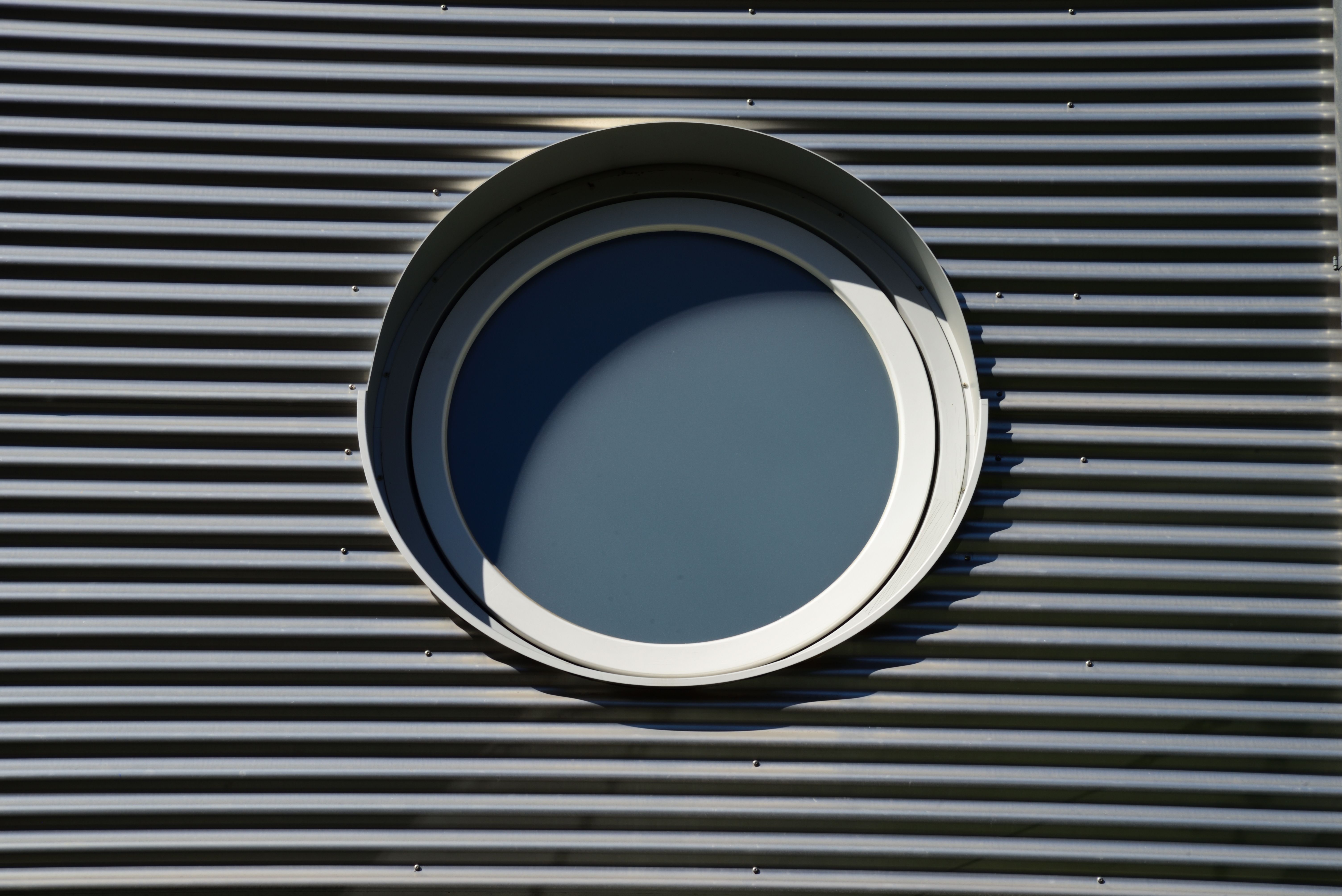 A round window in a metal facade, showcasing architectural design in Freiburg im Breisgau.