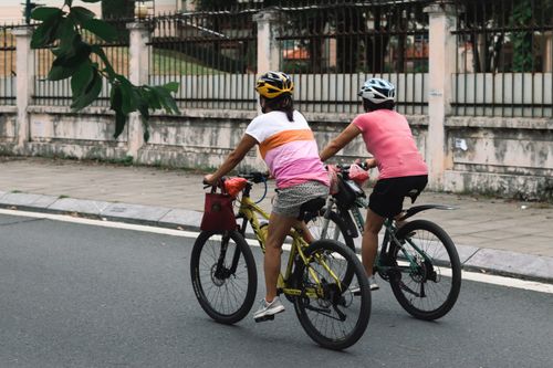 Free Two women cycling along an urban street wearing helmets, promoting outdoor fitness and health. Stock Photo