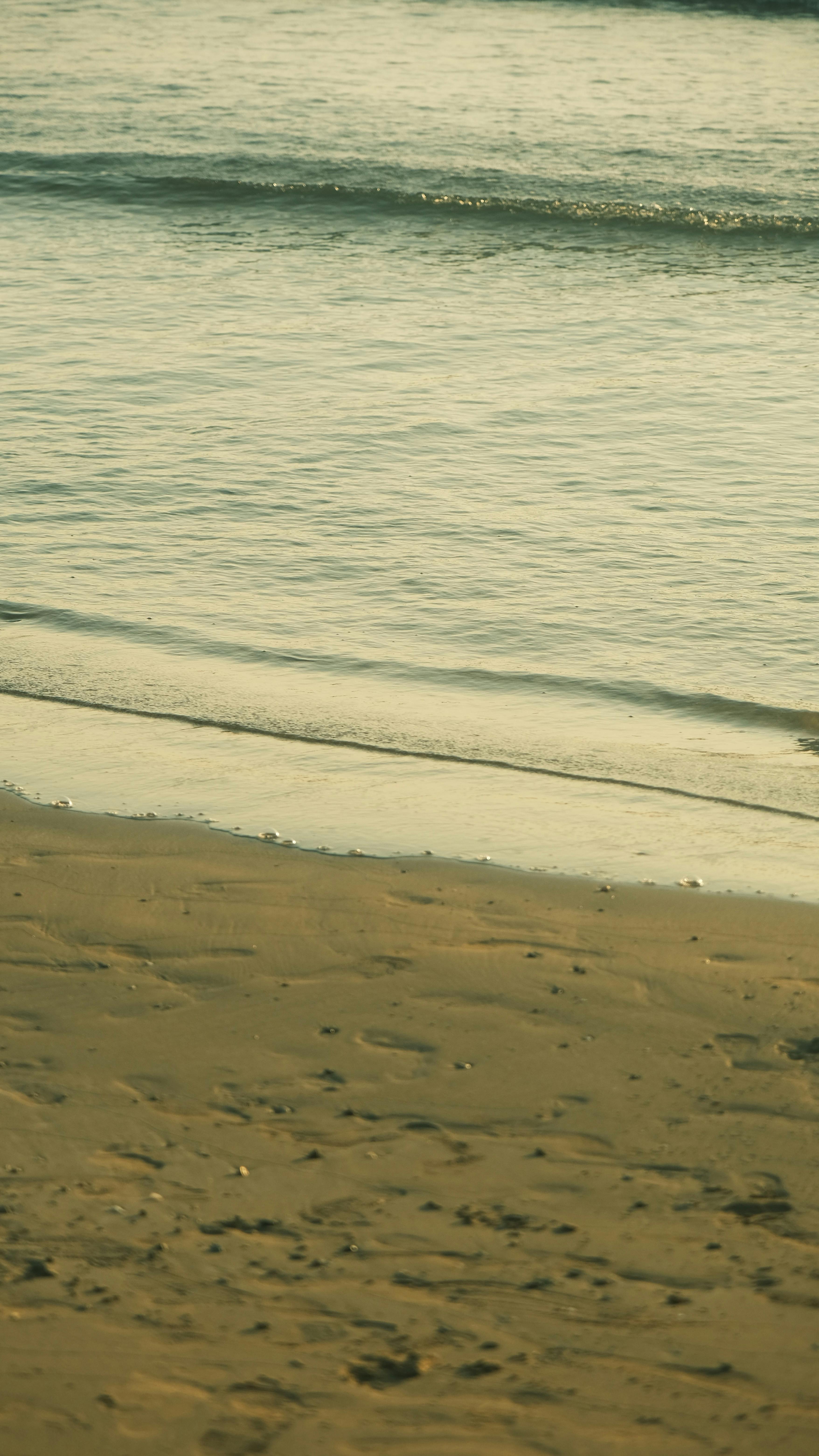 Zadarmo Pokojné pobrežie za súmraku s jemnými vlnami a mäkkým svetlom. Fotka z fotobanky
