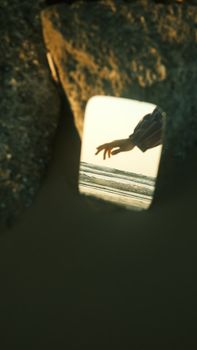 Creative shot of a hand in a mirror surrounded by rocks, evoking a serene, reflective mood.