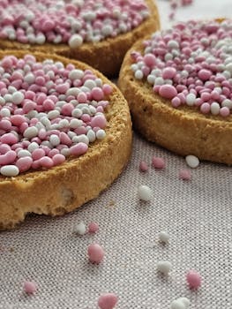 Close-up of toasted bread with pink and white sprinkles on a light fabric background.
