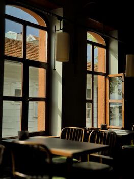Warm café interior with sunlit windows casting shadows on empty tables and chairs.