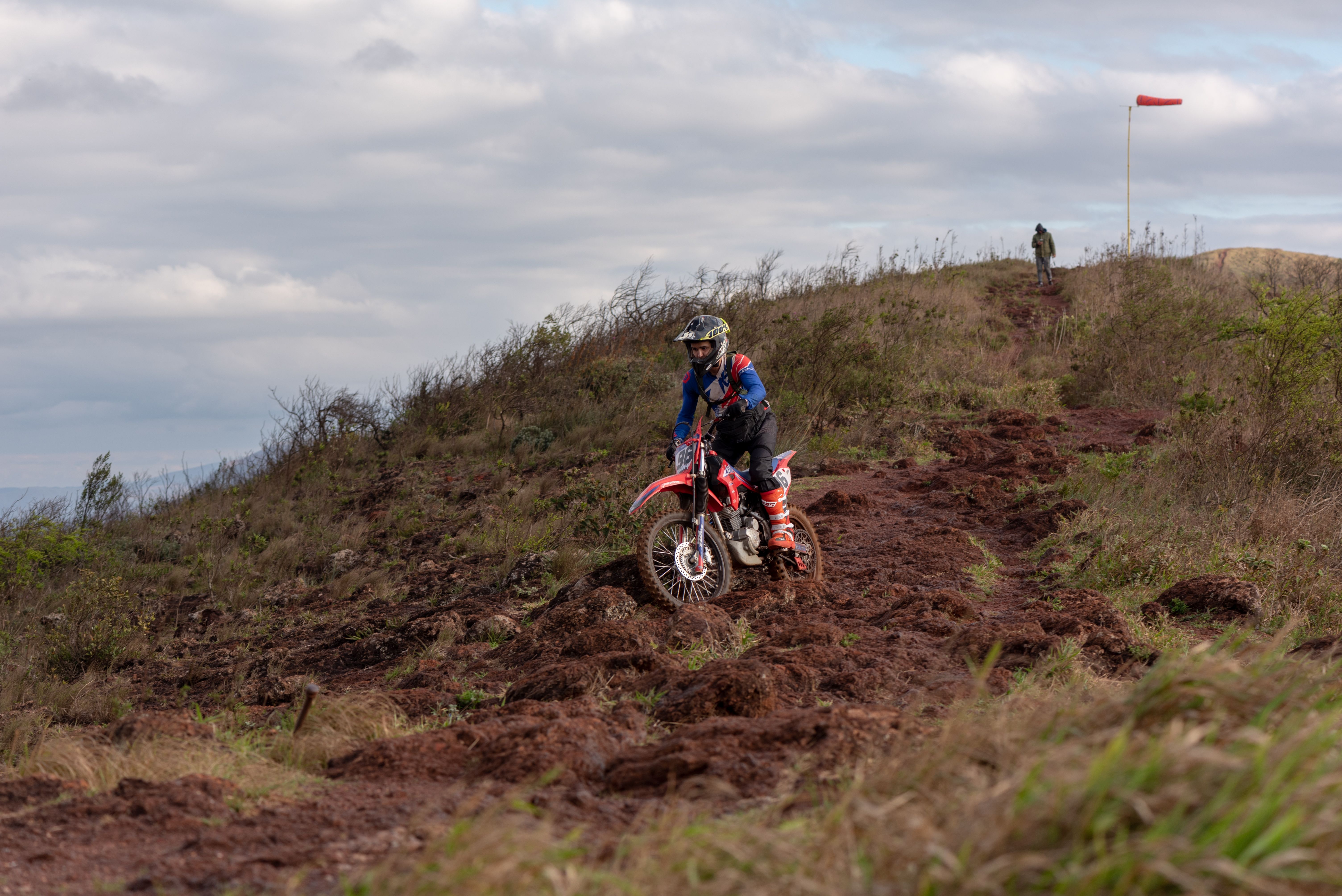 Rider navigating the rugged trails in Brumadinho, Minas Gerais, Brazil under a cloudy sky.