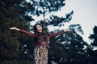 在森林的背景下，一个女人张开双臂，享受户外活动的自由与幸福