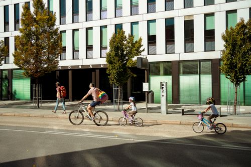 Free Family on bicycles enjoying a sunny day in Innsbruck, Austria, near modern buildings. Stock Photo