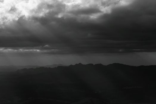 Black and white landscape of dramatic clouds casting shadows over mountains in Minas Gerais, Brazil.