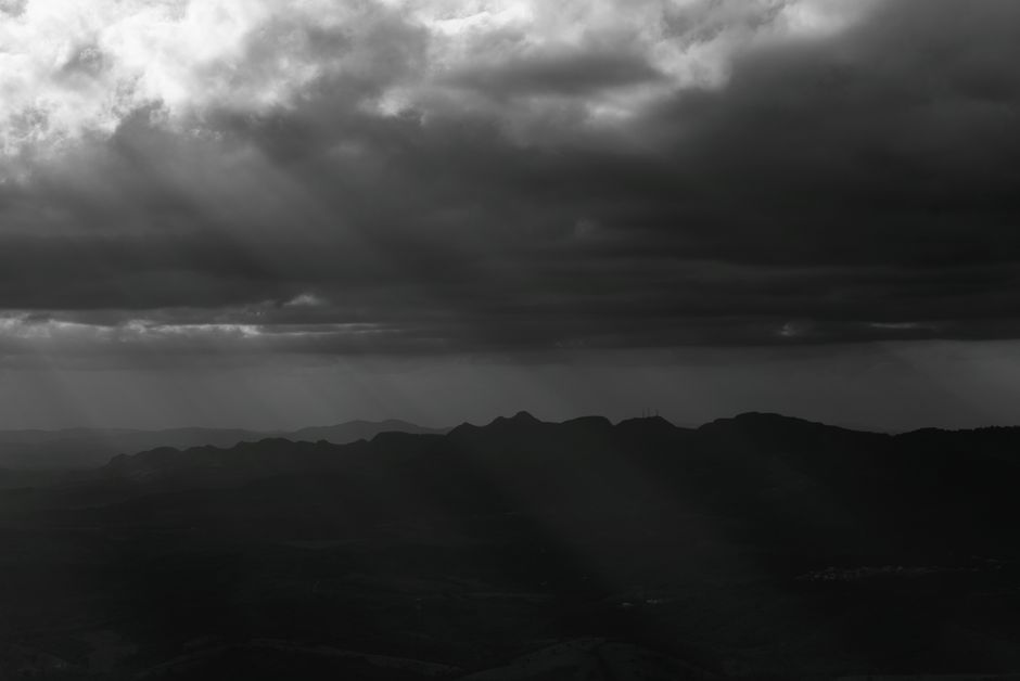Black and white landscape of dramatic clouds casting shadows over mountains in Minas Gerais, Brazil.
