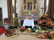 Vibrant harvest festival display with fruits, vegetables, and altar decorations in a church.