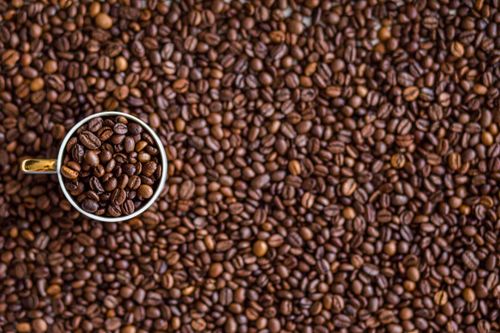 Free A top-down view of a coffee cup filled with coffee beans on a rustic coffee bean background. Stock Photo