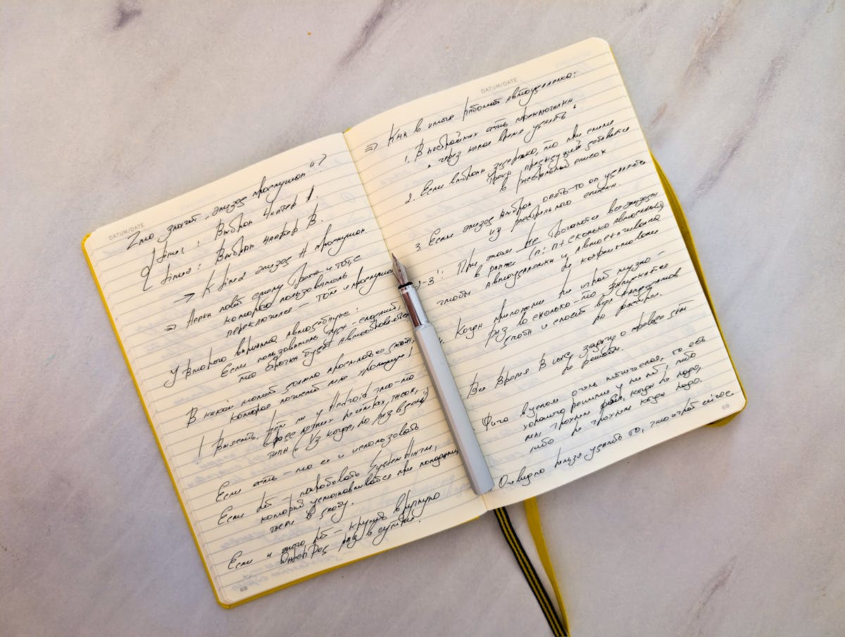 Quaderno aperto con appunti corsivi e una penna appoggiata sulle pagine