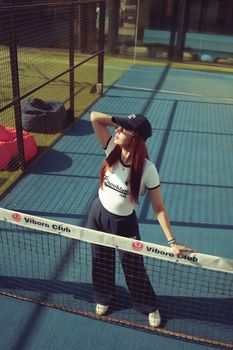 Woman in sports attire posing on a tennis court under bright sunlight at Vibora Club.