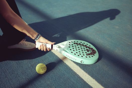 Padel player holding a racket on a sunlit court in Baghdad, Iraq.