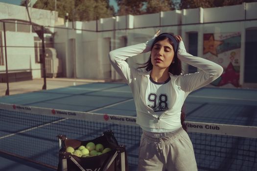 Woman stretching on a sunny day at a tennis court in Baghdad, capturing a relaxed and sporty vibe.