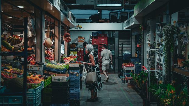 Vibrant market in Balearic Islands with diverse produce and shoppers exploring.