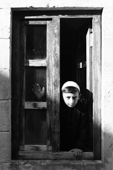 A boy in traditional attire looks out from a window in Şanlıurfa, Türkiye.