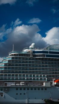Large cruise ship with numerous decks under a dramatic cloudy sky.
