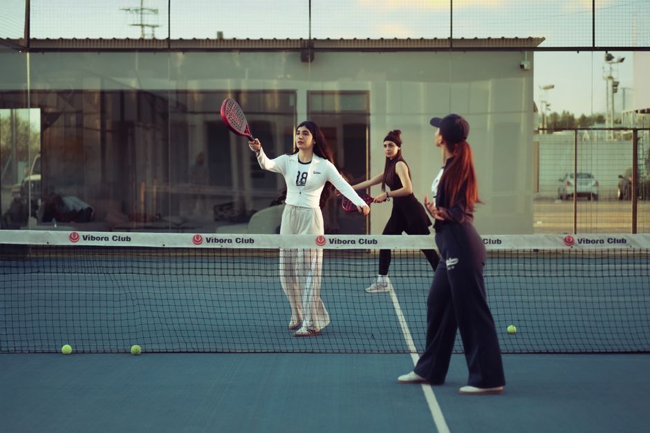 Three young women enjoying a padel match at Vibora Club in Baghdad, showcasing skill and teamwork.