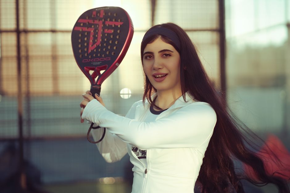 A Middle-Eastern woman enjoying a game of padel outdoors in Baghdad, Iraq.