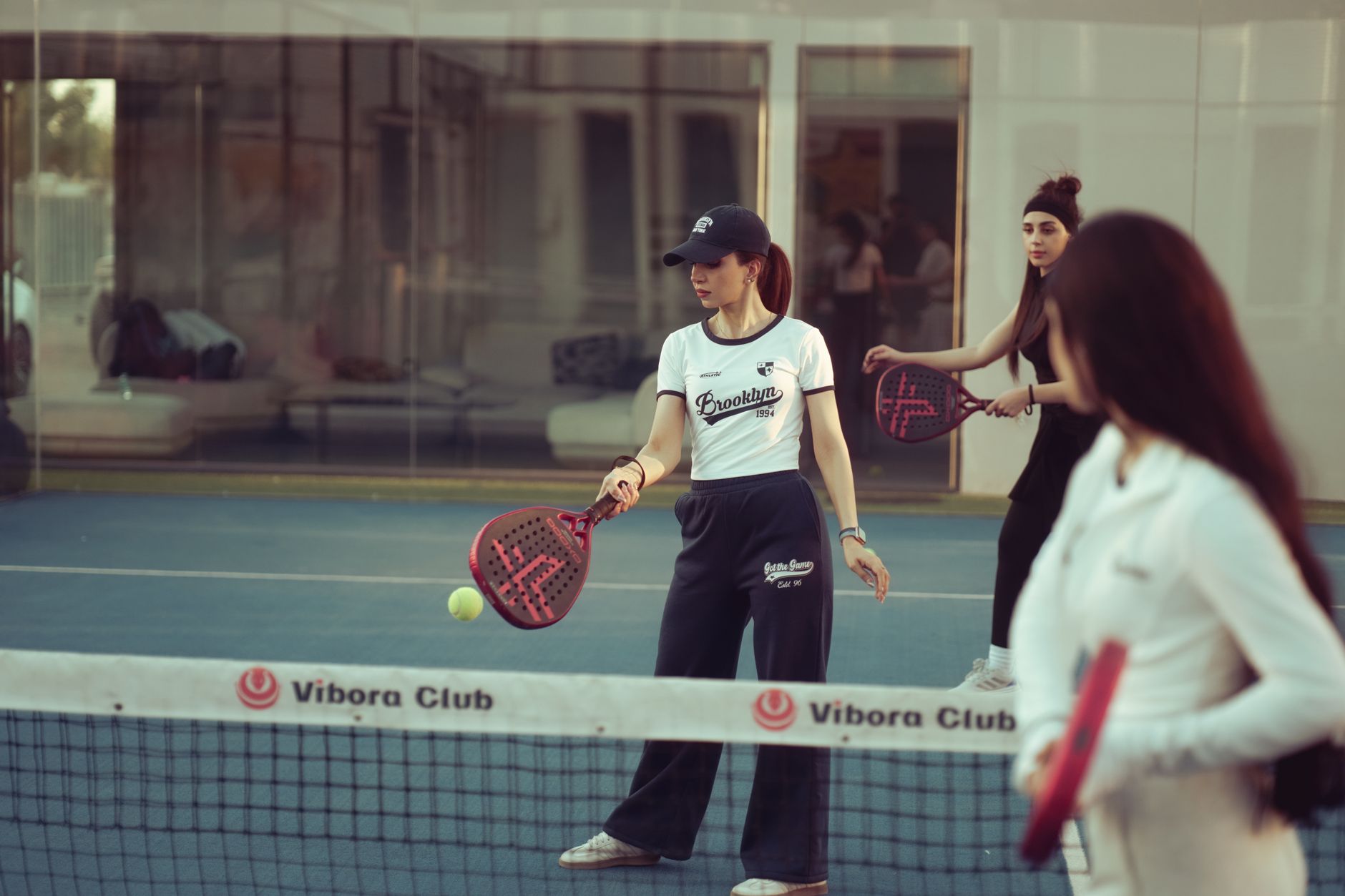 Women enjoying a padel match indoors at Vibora Club, Baghdad, showcasing athletic activity.