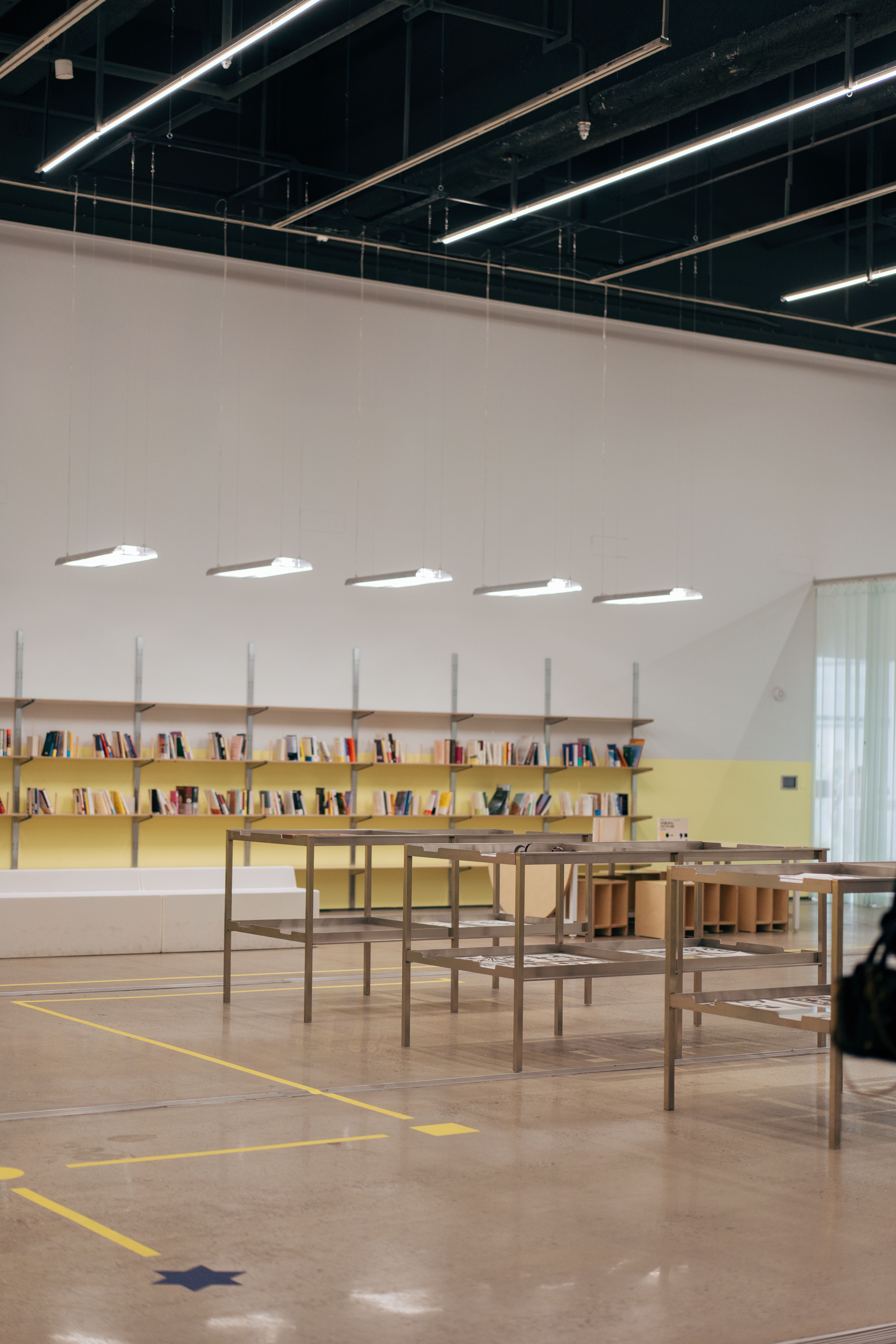 Spacious, minimalist library with bookshelves and tables, ideal for reading or studying.