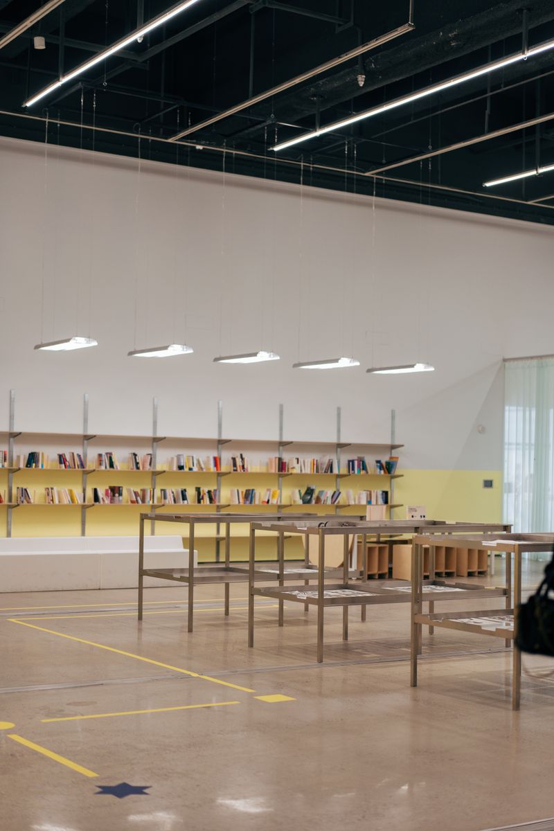 Spacious, minimalist library with bookshelves and tables, ideal for reading or studying.