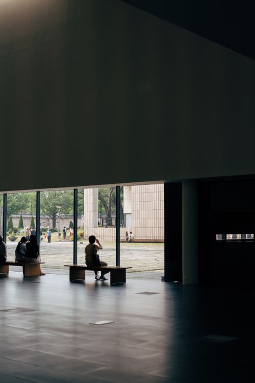 Free Silhouette of people inside modern building overlooking outside greenery. Stock Photo