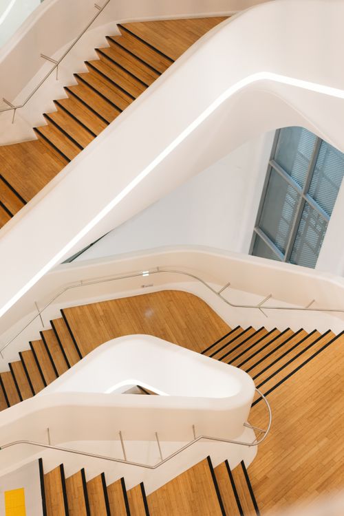 Free Abstract view of a modern staircase with wooden steps and sleek white railings. Stock Photo