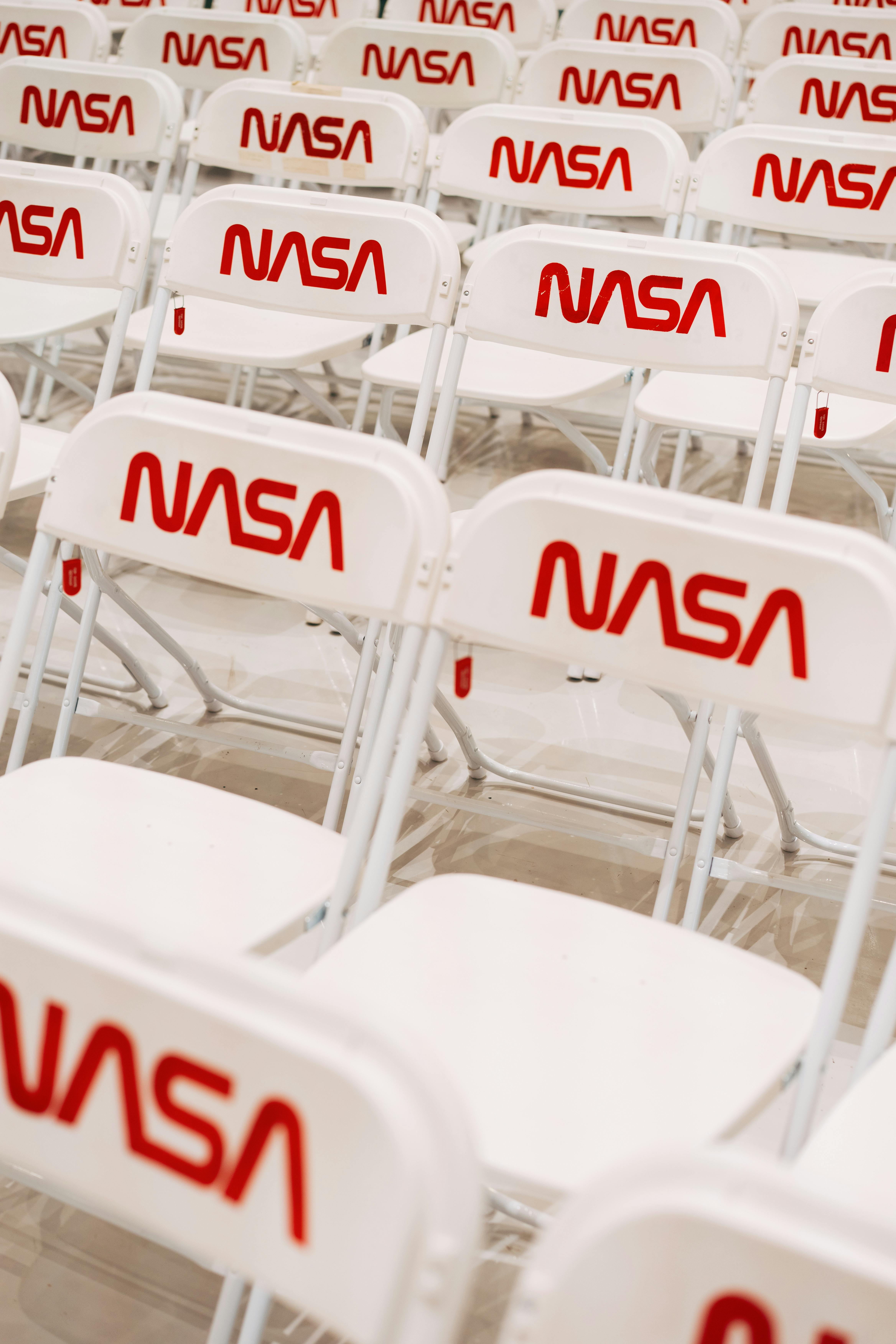 Rows of white chairs with NASA logo setup for indoor event seating.