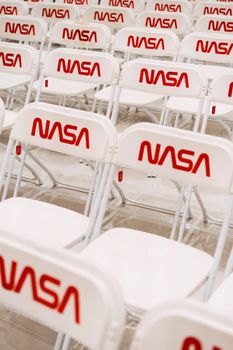Rows of white chairs with NASA logo setup for indoor event seating.